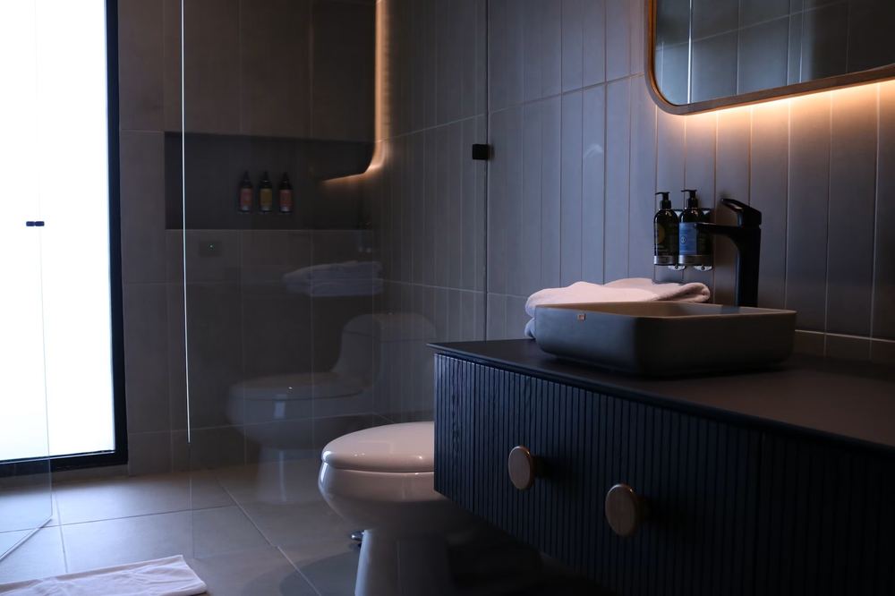 Finished bathroom remodel in Houston, TX with a floating vanity, vessel sink, and backlit mirror