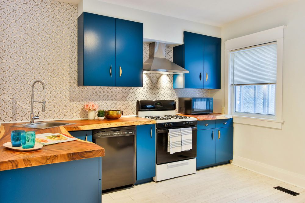 Finished kitchen remodel in Houston, TX with navy cabinetry, live-edge wood countertops, and a stainless range hood